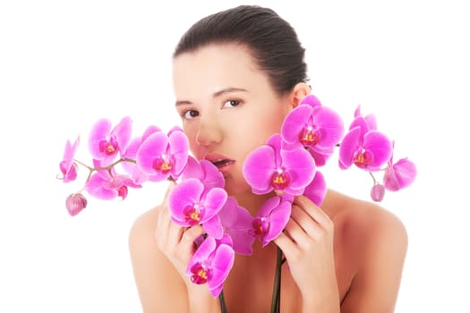 Portrait of beautiful young woman with health skin and with orchid flower. Spa concept.