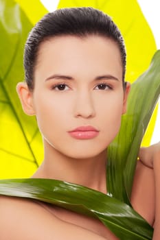 Portrait of young beautiful woman at spa with green leafs in background