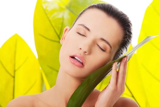 Portrait of young beautiful woman at spa with green leafs in background