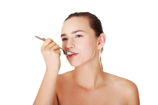 Teen girl with spoon in mouth. Isolated on white