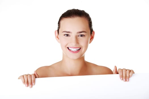 Beautiful teen girl behind big blank billboard, isolated on white background