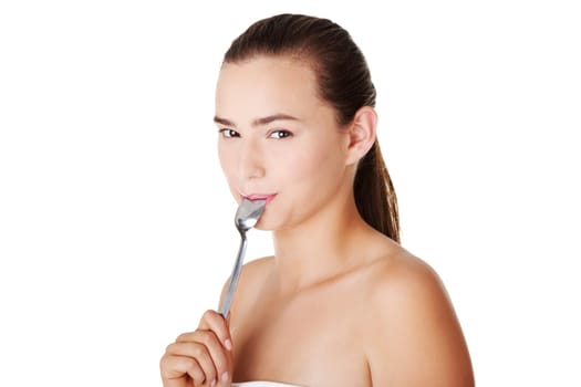 Teen girl with spoon in mouth. Isolated on white