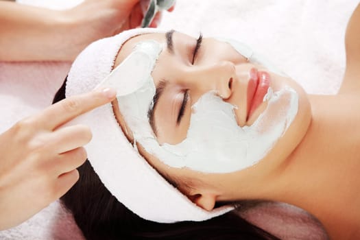 Beauty treatment in spa salon. Woman with facial clay mask.