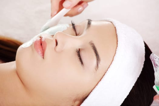 Beauty treatment in spa salon. Woman with facial clay mask.