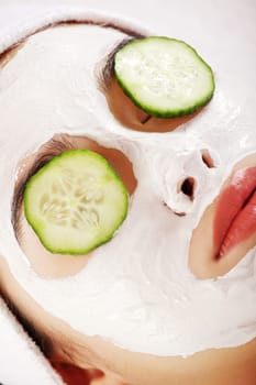 Young woman with cucumber slices on the face in a spa saloon