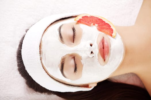 Attractive young woman with fruit mask on a face at spa saloon