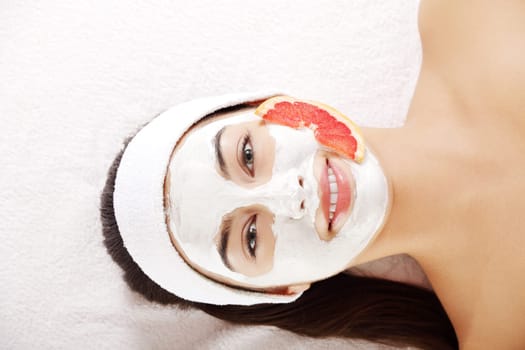 Attractive young woman with fruit mask on a face at spa saloon