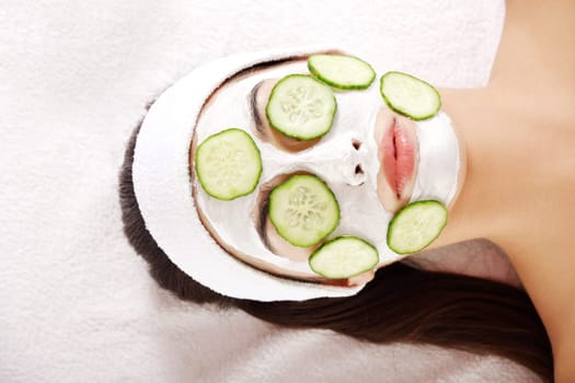 Young woman with cucumber slices on the face in a spa saloon