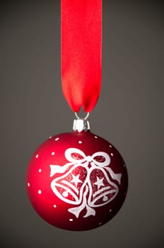 beautiful red christmas toy ball hanging on the red ribbon against dark grey background