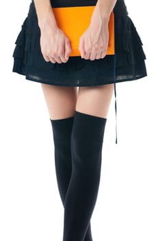 view of the lower body part isolated on white background of woman wearing skirt, stockings holding book in her hands