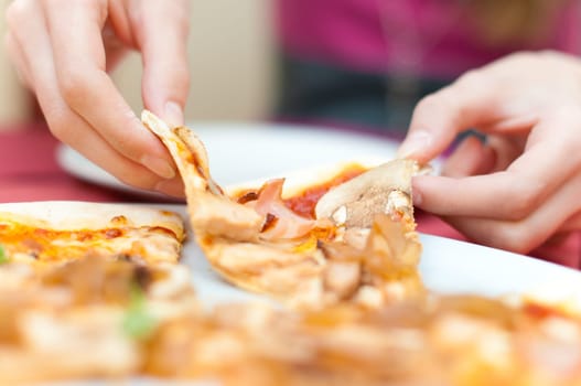 young girl taking slice of tasty meat pizza from the plate (shallow depth of field)