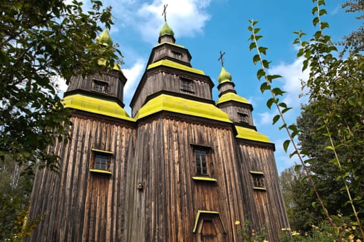 beautiful old wooden church in forest with blue cloudy sky in background