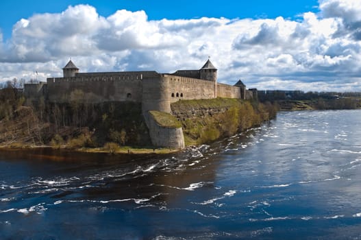 russian fortress of Ivangorod with river in foreground and blue cloudy sky in background