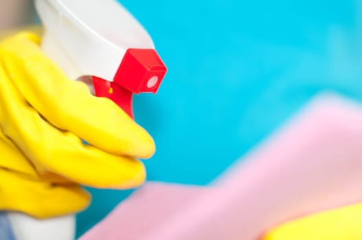 woman in protective yellow gloves holding sprayer and duster in her hands (shallow depth of field, focus on the nose of the sprayer)