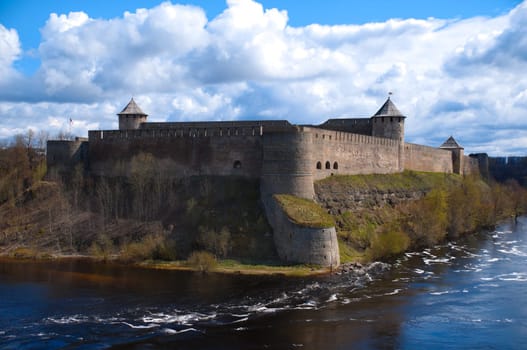 russian fortress of Ivangorod with river in foreground and blue cloudy sky in background