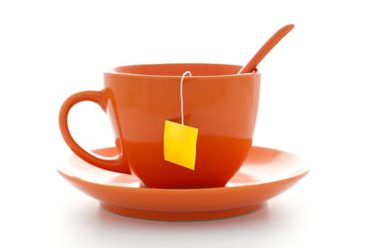orange cup of tea with saucer and tea bag inside with empty yellow label