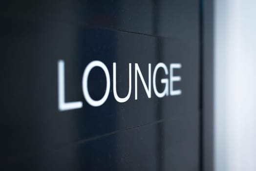 Close up view of black sign with big white inscription Lounge. Having rest or comfortable waiting of flight with good service at airport. Business trips and travelling.