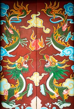Bright colorful painting with dragons on door of building in Vietnam. Double folding ancient doors with symmetric pattern of green dragons on it. Vietnamese art, culture and religion.