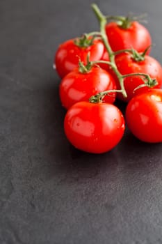 Closeup of bunch of fresh red tomatoes on dark background