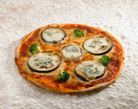 A tasty pizza eggplant on a bed of flour.