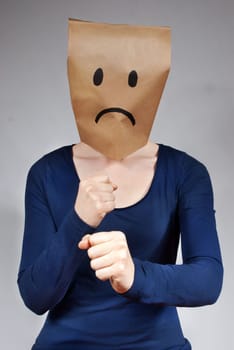 a woman with a a sad paper bag head defending herself
