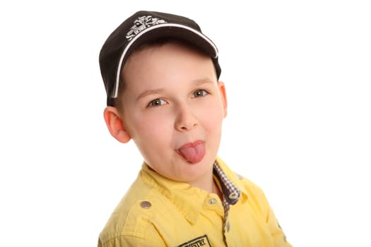 Portrait photo of a boy wearing a baseball cap and looking into the camera with his tongue outstretched.
