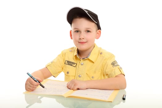 The little boy sits in front of a notebook and looks friendly,smiling into the camera