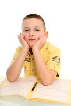 A little boy sits sadly at a table and looks into the camera.