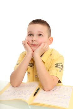 A schoolboy sits at a desk and looks up bored. A loose-leaf folder lies open in front of it.