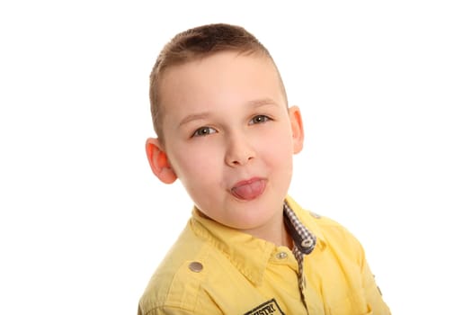 Portrait photo of a little boy cheekily sticking out his tongue and looking into the camera.