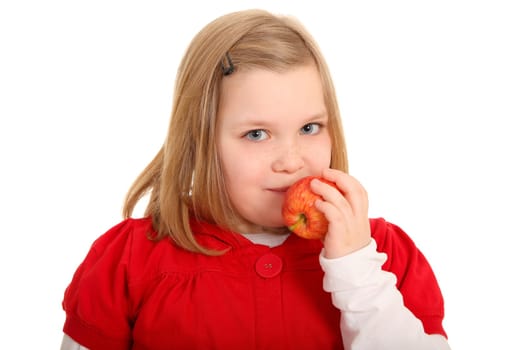 A little girl wants to eat an apple and looks directly into the camera.