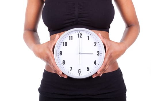 Young black african american woman holding a clock in front of her belly, isolated on white background - African people