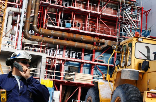 building worker talking in phone inside large construction site.