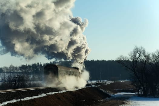 Vintage steam train puffing through countryside during wintertime