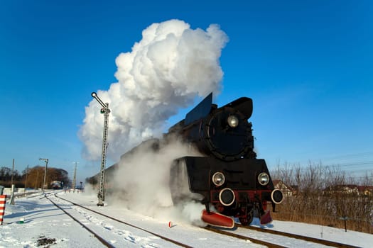 Vintage steam train puffing through countryside during wintertime