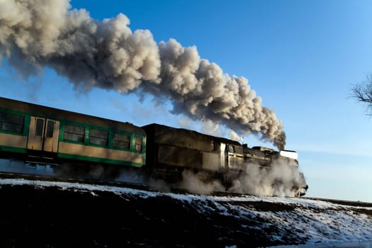 Vintage steam train puffing through countryside during wintertime