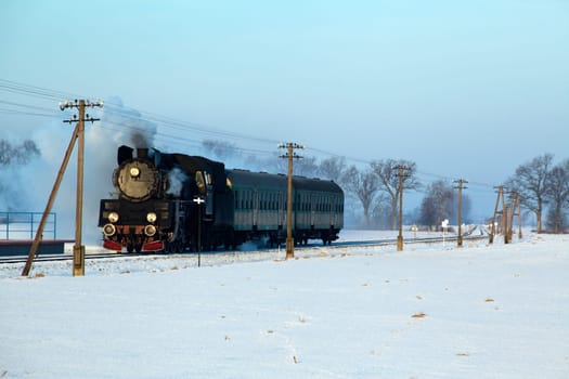 Vintage steam train puffing through countryside during wintertime