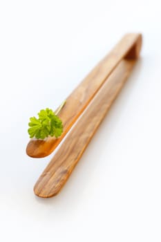 Close up of a barbecue wooden tongs, short depth of field with a sprig of parsley on top.