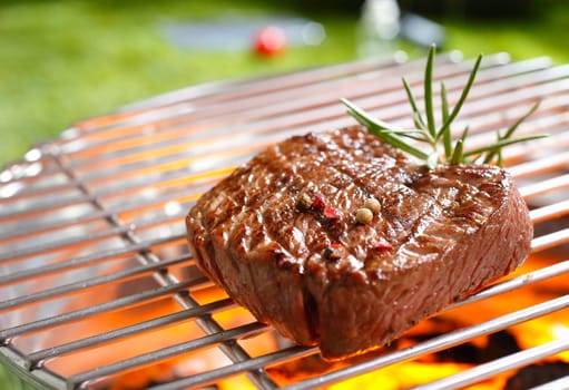 A thick strip steak being grilled outdoors