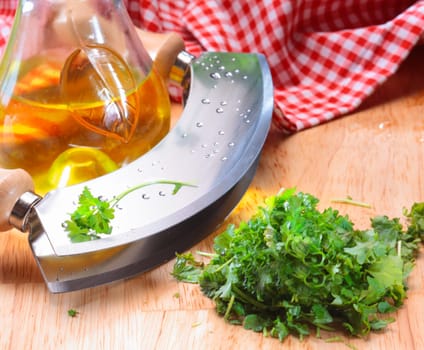 Modern herb cutter (wiegemes) with wooden handles and a clump of flat head parsley.