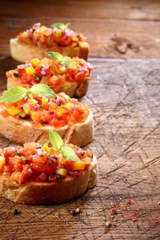 Row of delicious toasted crusty baguette with tomato bruschetta, an Italian antipasti served on grilled or toasted bread, on an old wooden table top