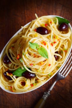Top view of spaghetti pasta with olives in a bowl with a fork.