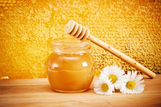 Jar of honey and flovers. On the background of honeycombs