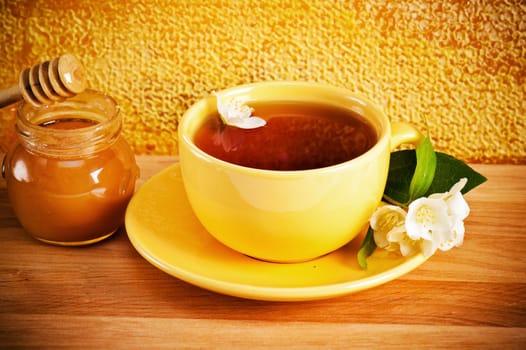 Cup of tea with a flower of a jasmin and honey