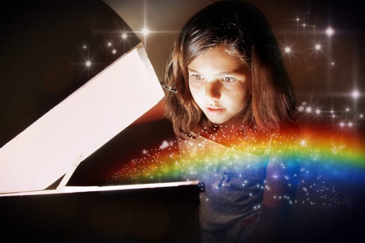A little girl opening a magic chest and setting the rainbow free amongst glittering stars. Christmas or birthday concept  the magic of gifts.