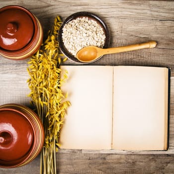 The top view on the opened cookbook and kitchen utensils
