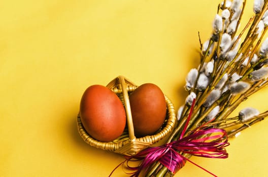 bunch of willow branches and two Easter eggs in basket