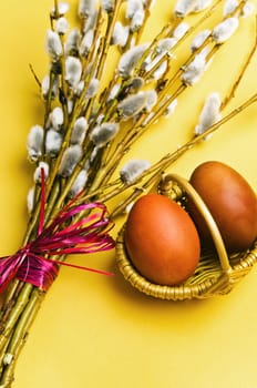 bunch of willow branches and two Easter eggs in basket