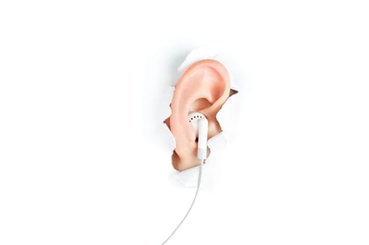 woman ear with headphones peeping out from white torn paper