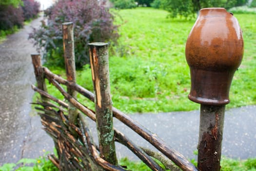 pot on wooden farm fence with grass and tree in background
